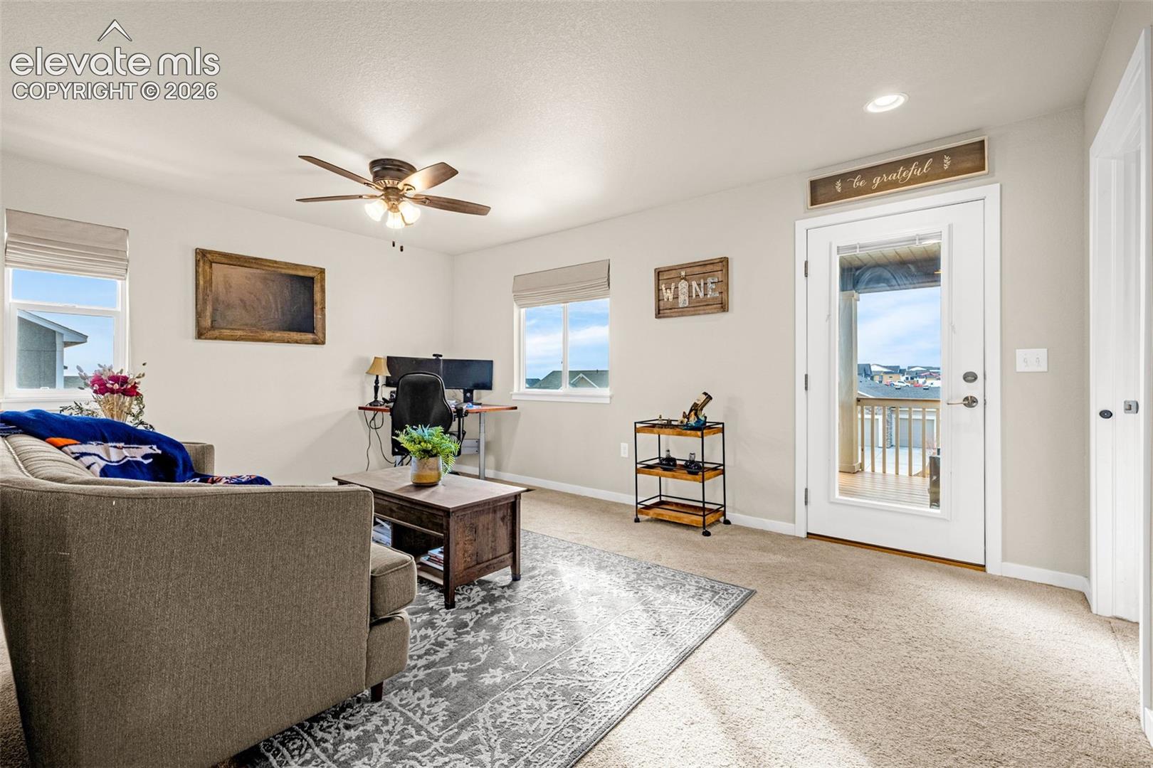 Carpeted room featuring a ceiling fan with integrated lighting, recessed lighting, and a glass-paneled door
