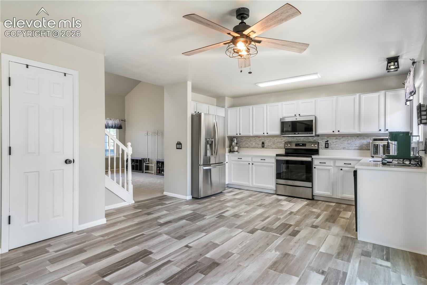 Kitchen with new LVP floors, stainless steel appliances, pantry and abundant cabinets and access out to patio