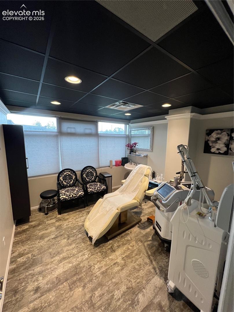 Room featuring wood-finish flooring, a dark grid ceiling with recessed lighting, and a built-in sink