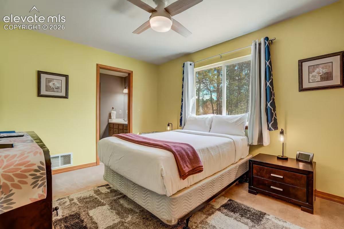 Bedroom featuring a ceiling fan, a window with outdoor scenery, and light-colored walls