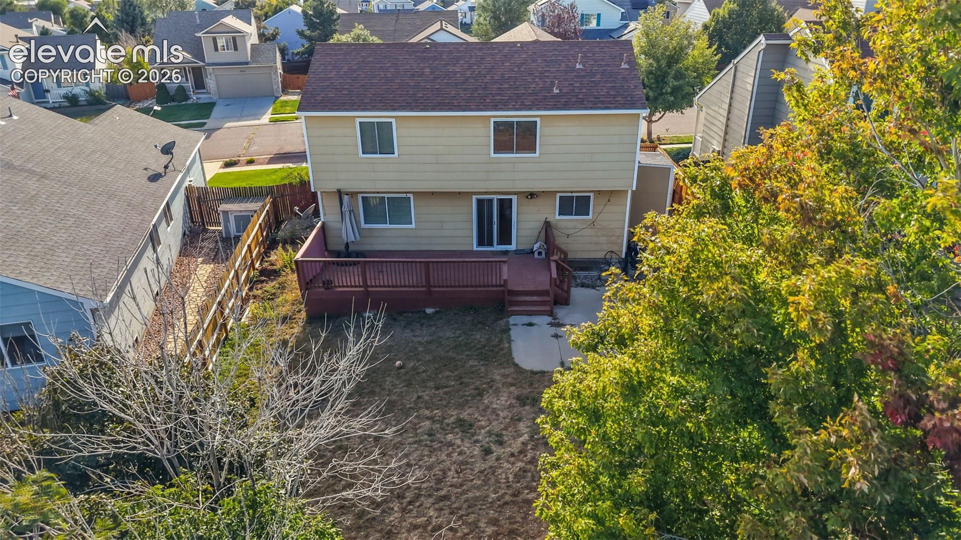 Spacious rear yard featuring a multi-level wood deck, concrete patio, and mature perimeter trees