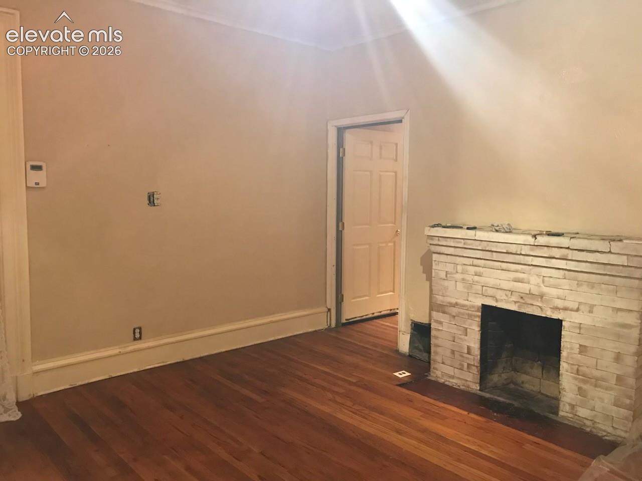 Hardwood flooring, crown molding, and a brick-finish fireplace