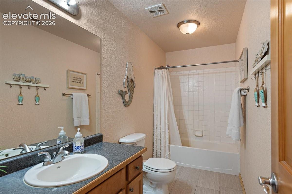 Upstairs bathroom 2 featuring a single vanity with an integrated sink, dark countertop, and wood-finish cabinetry