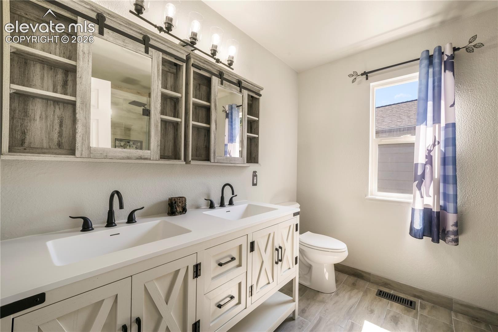 Upstairs primary updated bathroom with large walk in shower and dual vanties