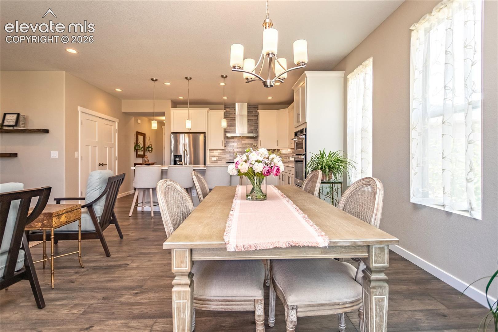 Open-concept living area with wood-finish flooring, recessed lighting, and a modern chandelier