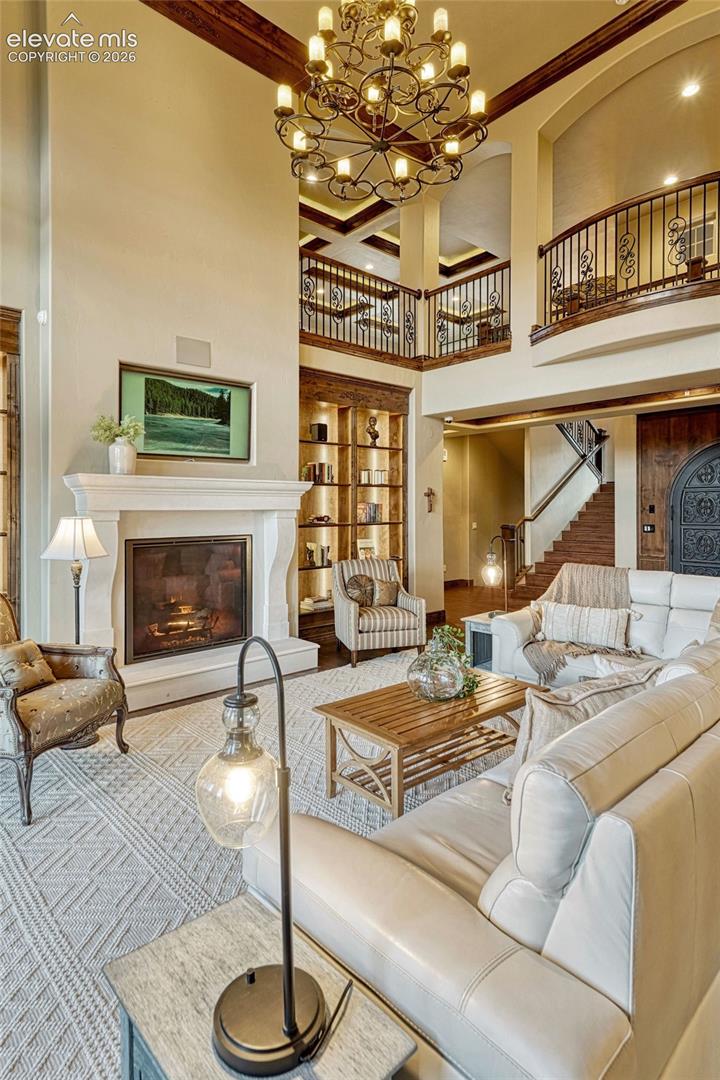 Two-story living area with a grand chandelier, stone fireplace, and built-in shelving