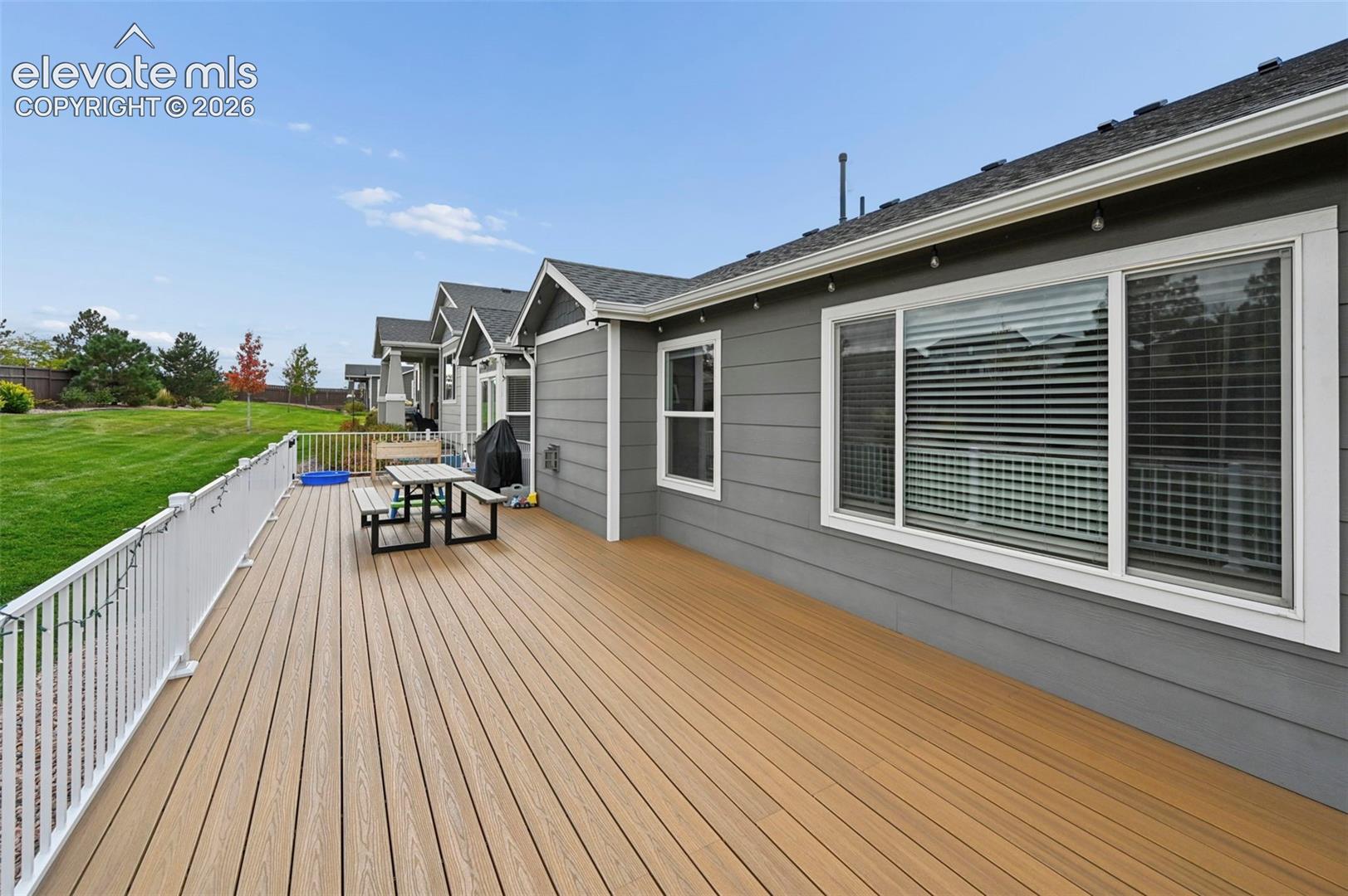 Composite deck featuring white metal railing, horizontal lap siding, and dual-pane windows