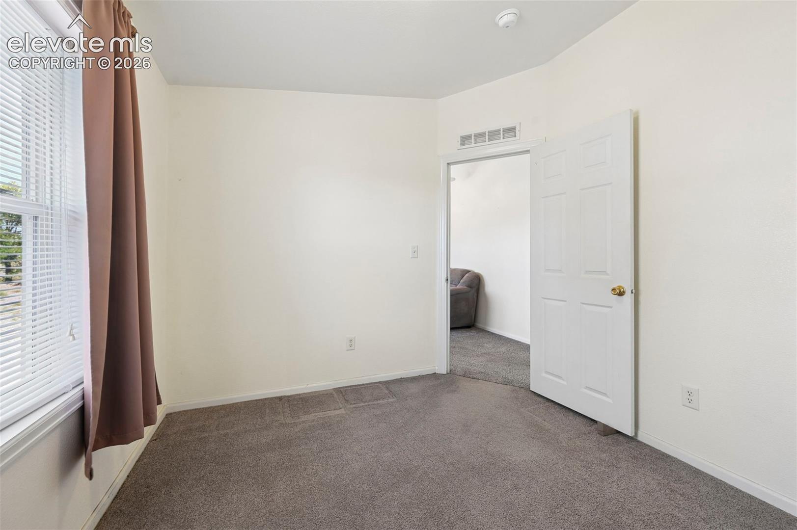Neutral interior featuring grey carpeting, off-white wall finishes, and a six-panel swing door