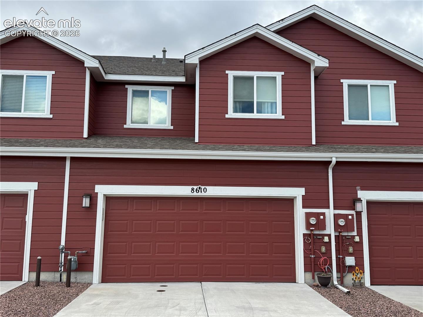 Multi-level exterior featuring horizontal siding, a gabled roofline, sliding windows, and a wide attached garage with a paneled door
