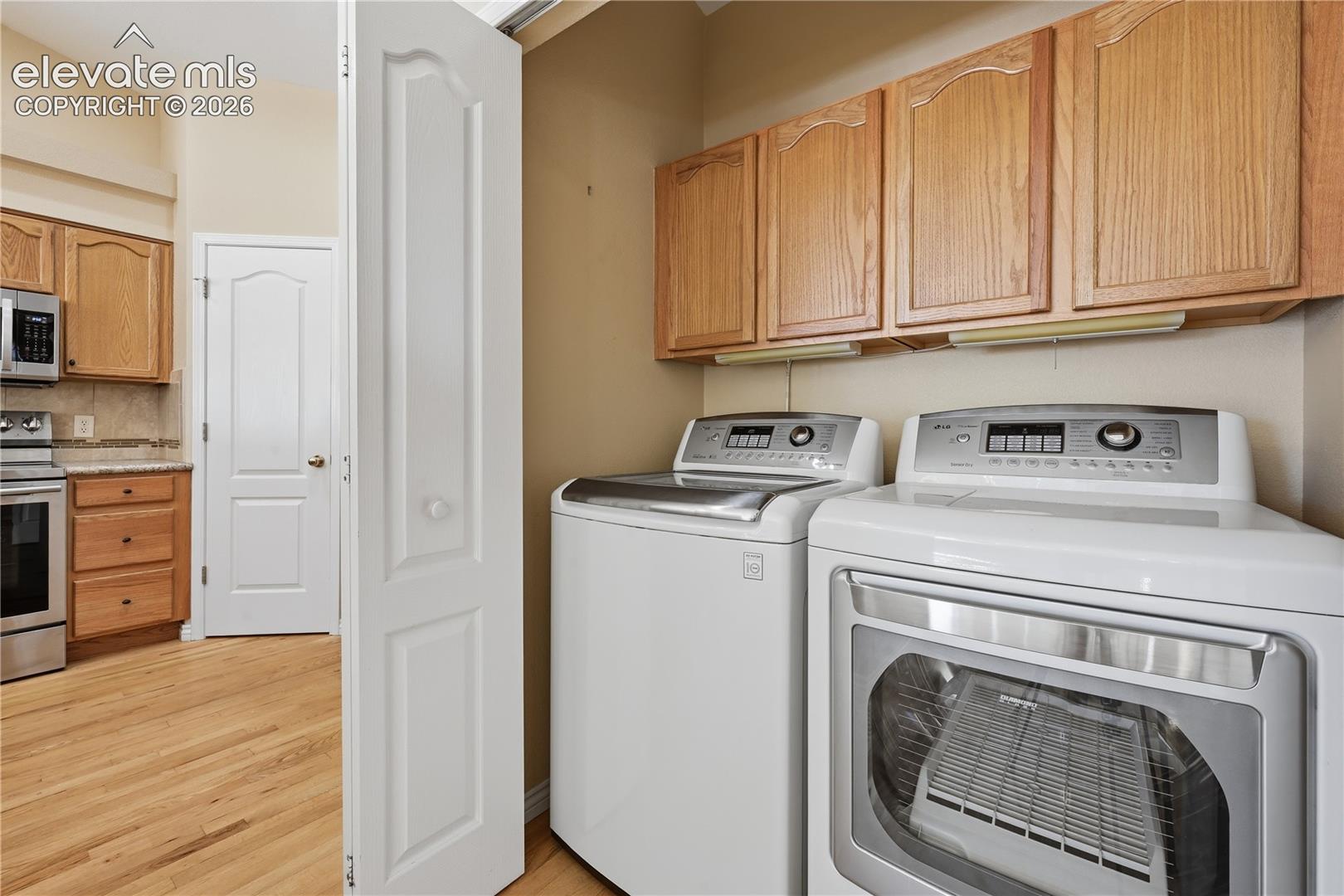 Laundry area featuring wooden cabinetry, under-cabinet lighting, and wood-finish flooring