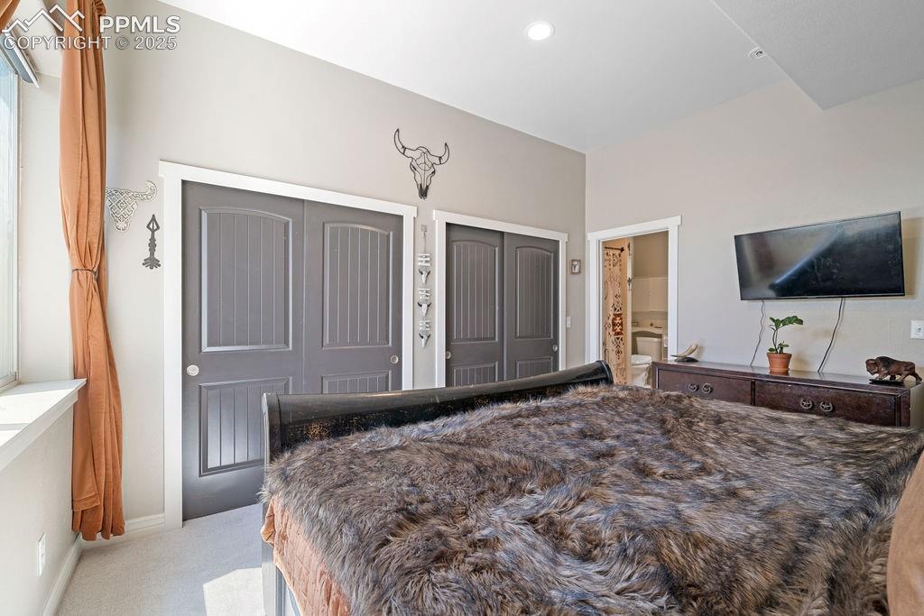 Bedroom featuring multiple closets, light colored carpet, recessed lighting, and connected bathroom