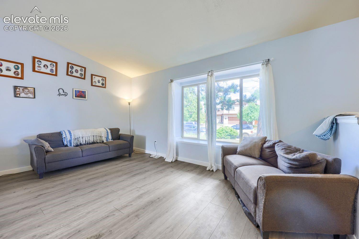 Wood-finish flooring with a light tone, vaulted ceiling, and dual-pane windows
