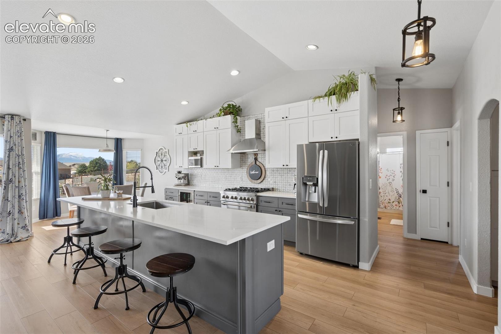 Kitchen featuring a large island with white countertops, stainless steel appliances, a tile backsplash, and luxury vinyl flooring