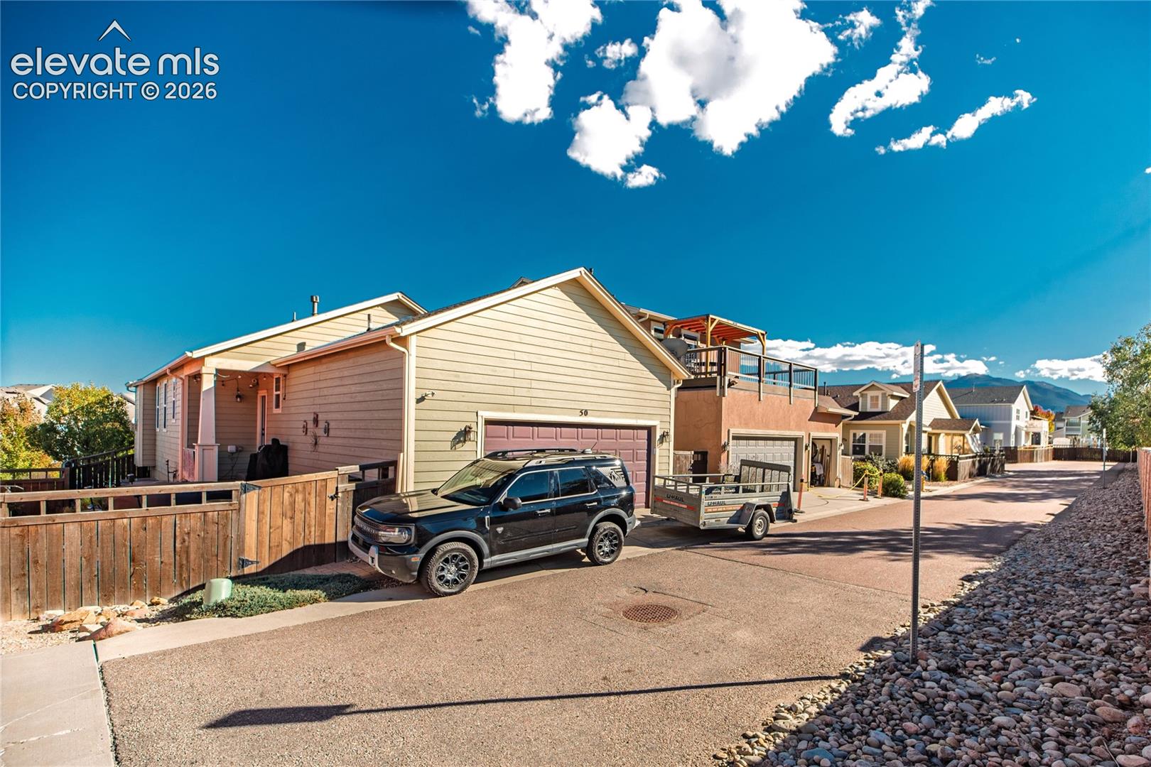 Two-story residence featuring horizontal lap siding, a two-car garage with a paneled door, and an upper-level balcony with metal railing