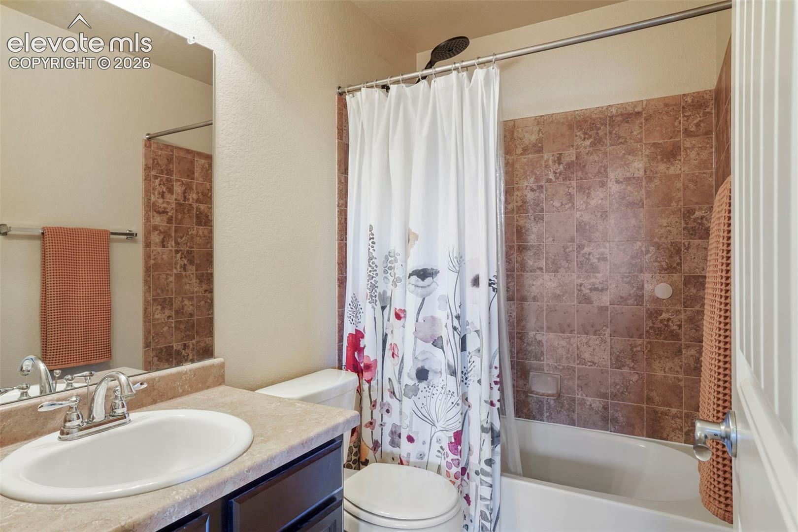 Integrated vanity with an oval sink, chrome faucet, and tan-toned countertop