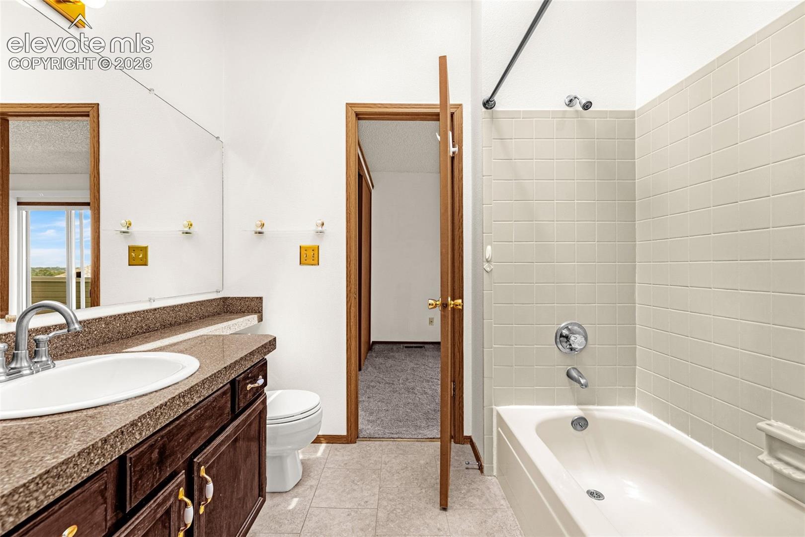 Bathroom featuring a single vanity with a dark wood-finish cabinet, integrated sink, and speckled countertop
