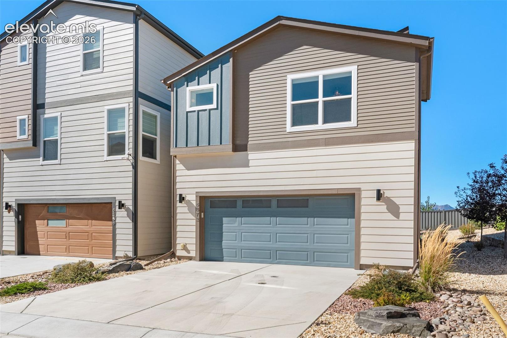 Modern exterior featuring multi-toned horizontal lap siding, vertical board-and-batten accents, a paneled garage door, and a concrete driveway