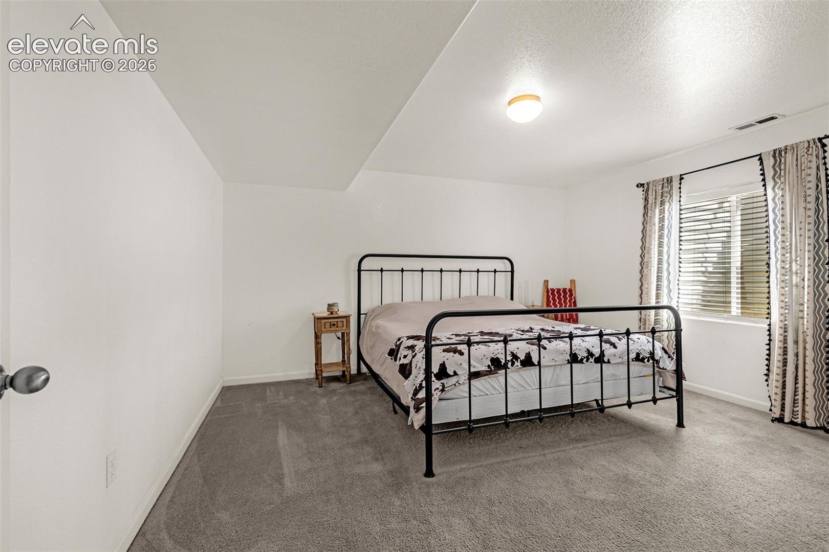 Recessed ceiling, neutral wall paint, carpet flooring, window with blinds, and flush mount lighting