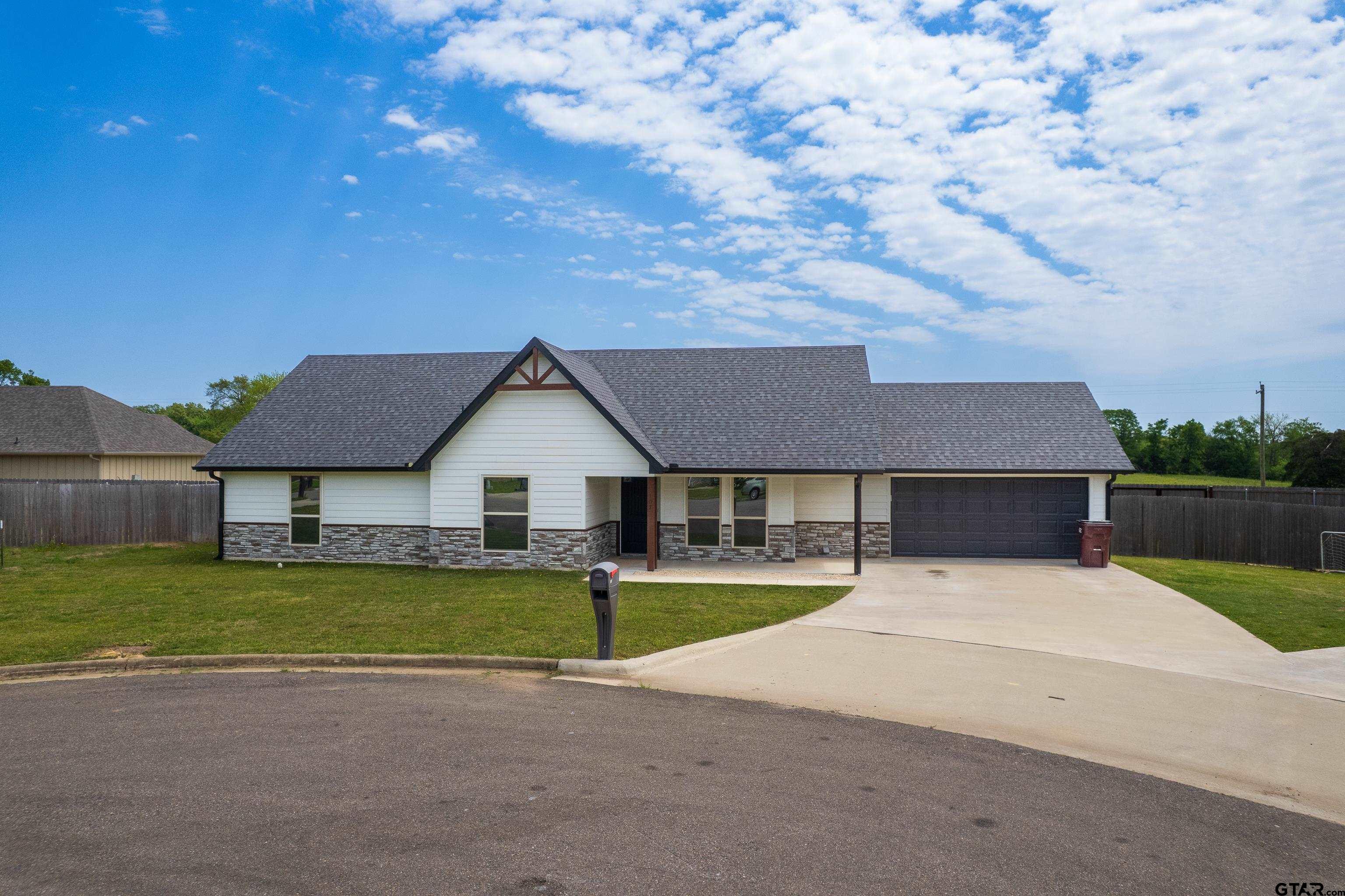 Single-story white house with stone veneer, a dark roof, and an attached garage.