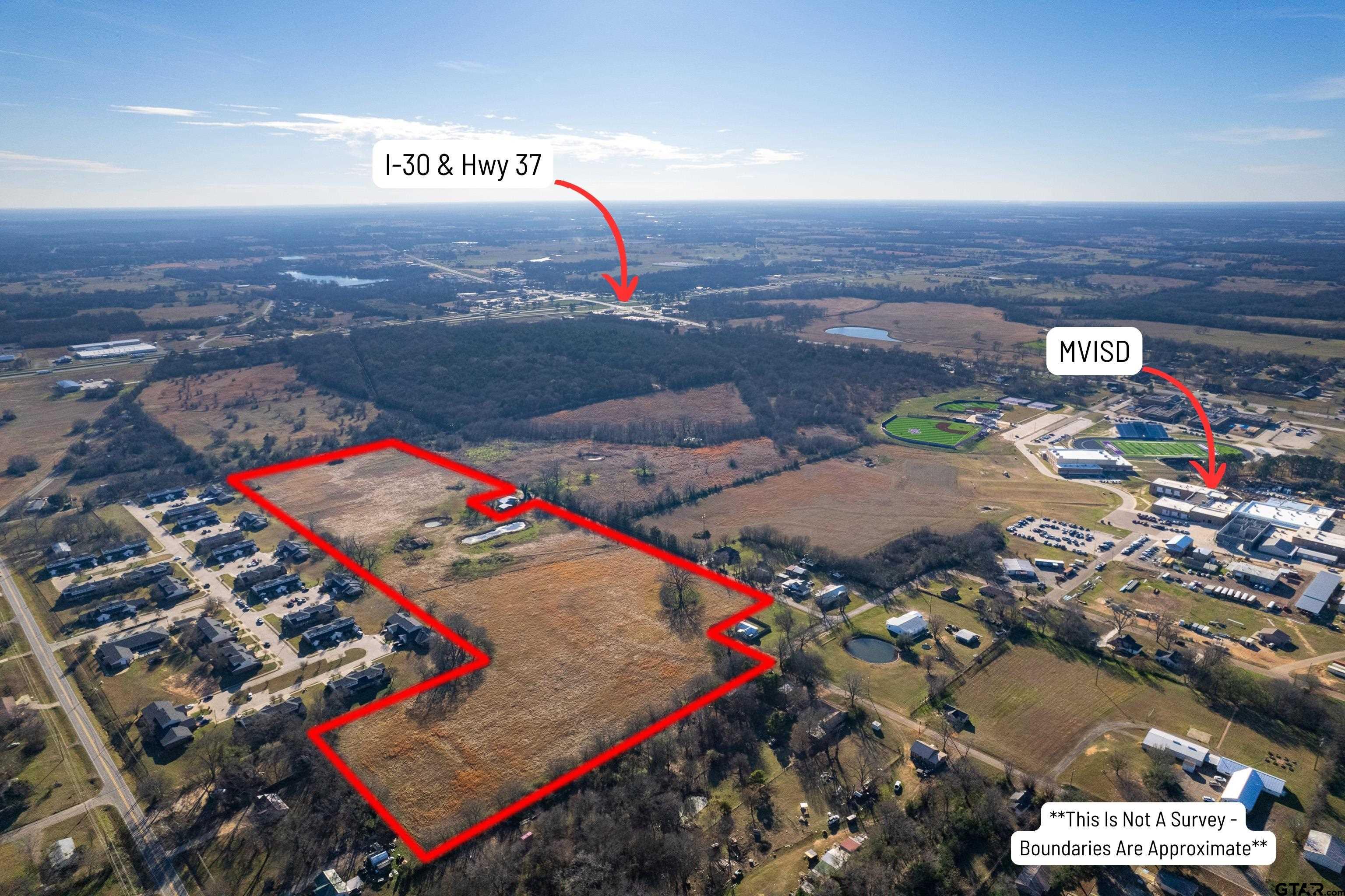 Aerial view of a large red-outlined vacant tract near Mount Vernon, with a school campus and highways nearby.