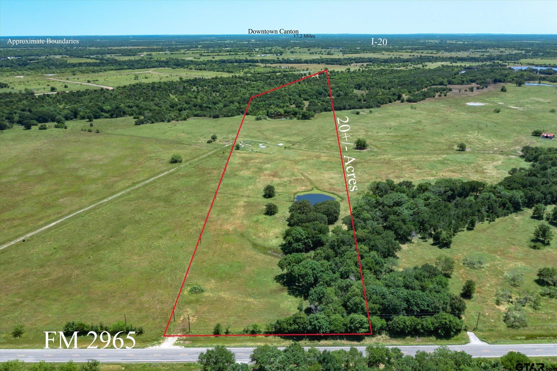 Aerial view of an approximately 20-acre pasture with a pond, wooded area, and FM 2965 frontage.