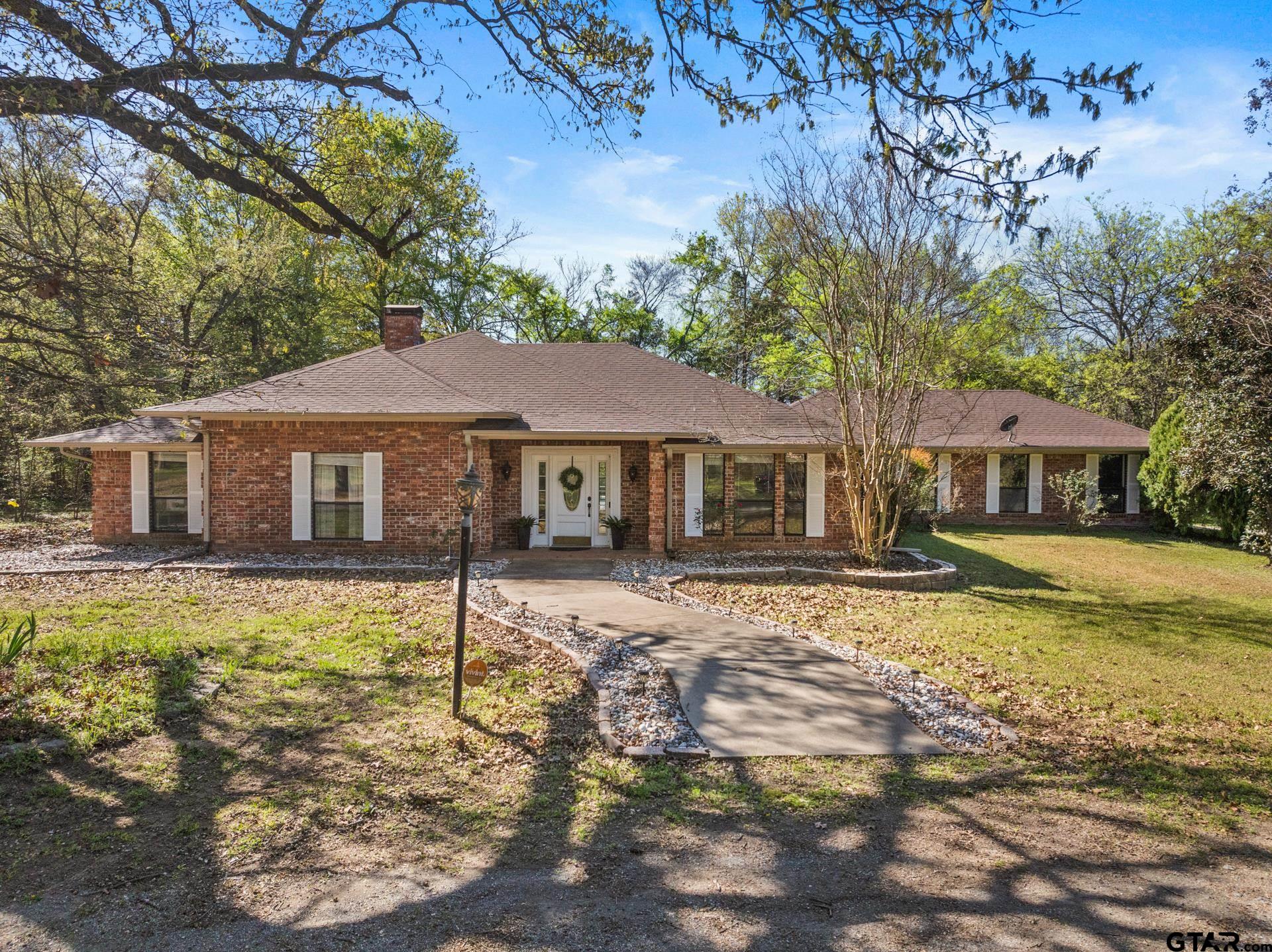 Single-story brick house with white shutters, a covered entry, and a curved front walkway.