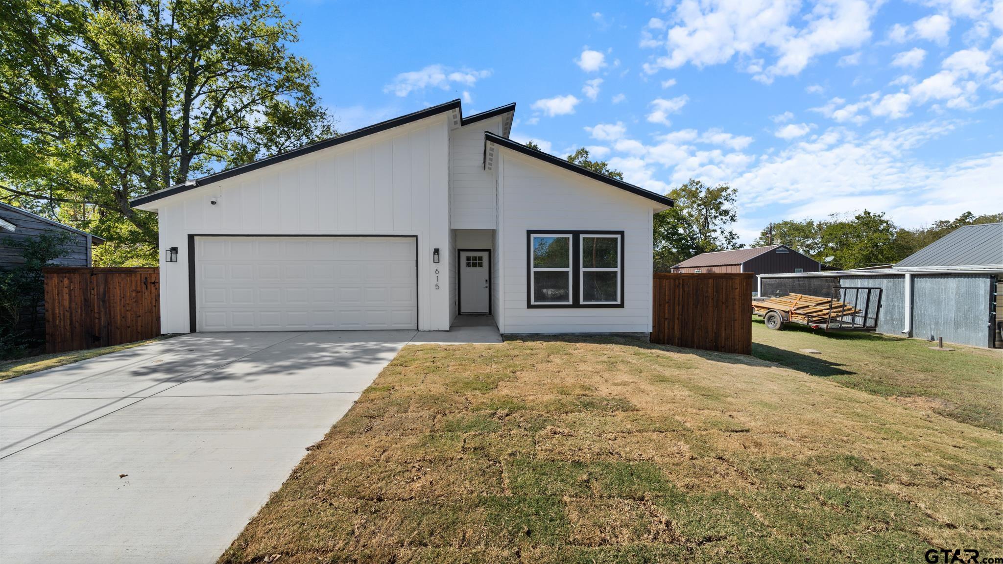 Modern white house with black trim, a wide garage, and a concrete driveway.