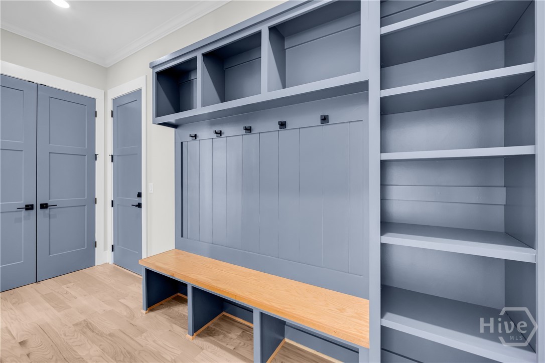 Integrated custom built-in cabinetry featuring shelving, coat hooks, and a wooden bench