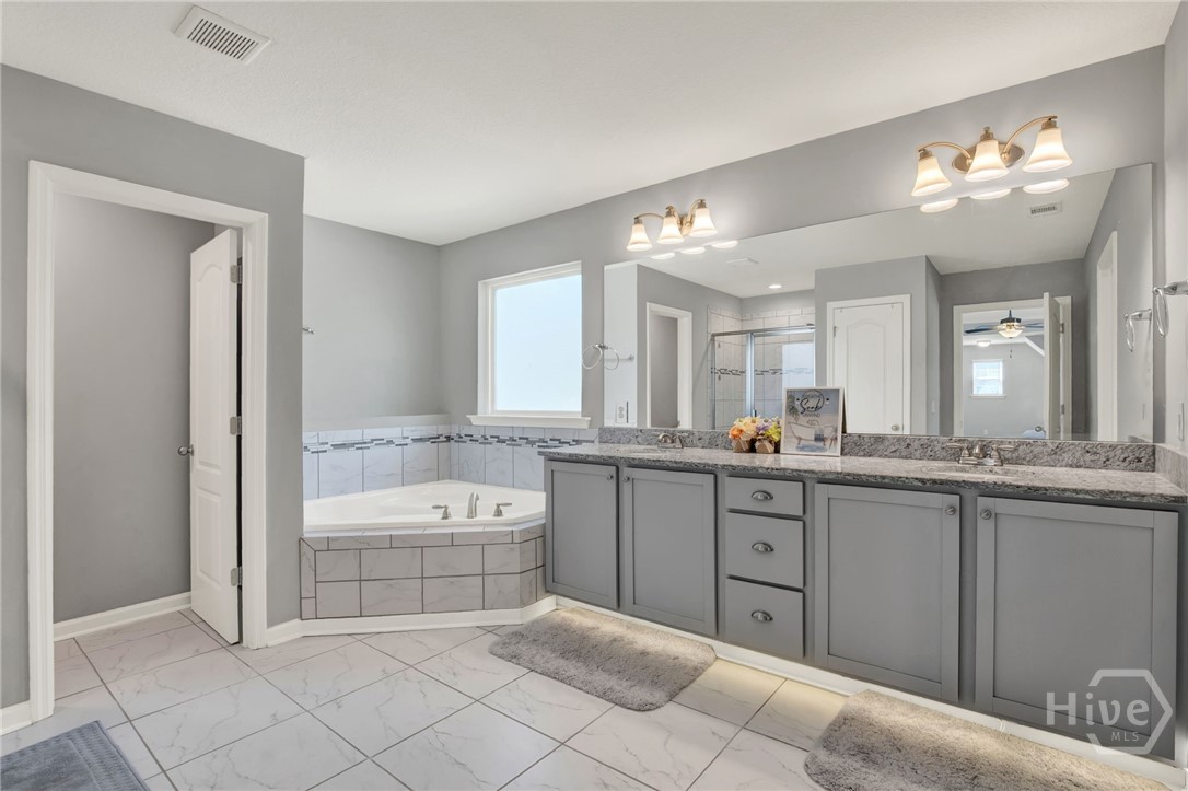 Primary Ensuite with Corner Soaking Tub, Separate Shower, Walk-In Closet, and Under-Cabinet Lighting