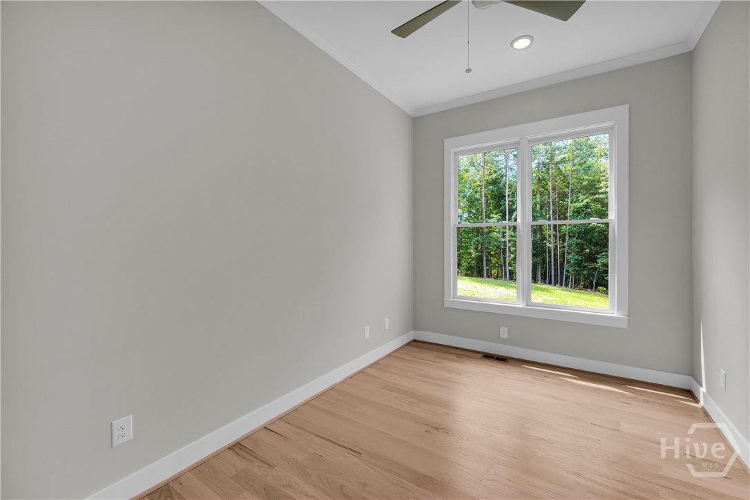 Light-filled guest bedroom on main featuring a double-hung window, wood-finish flooring, a ceiling fan, recessed lighting, and crisp white trim