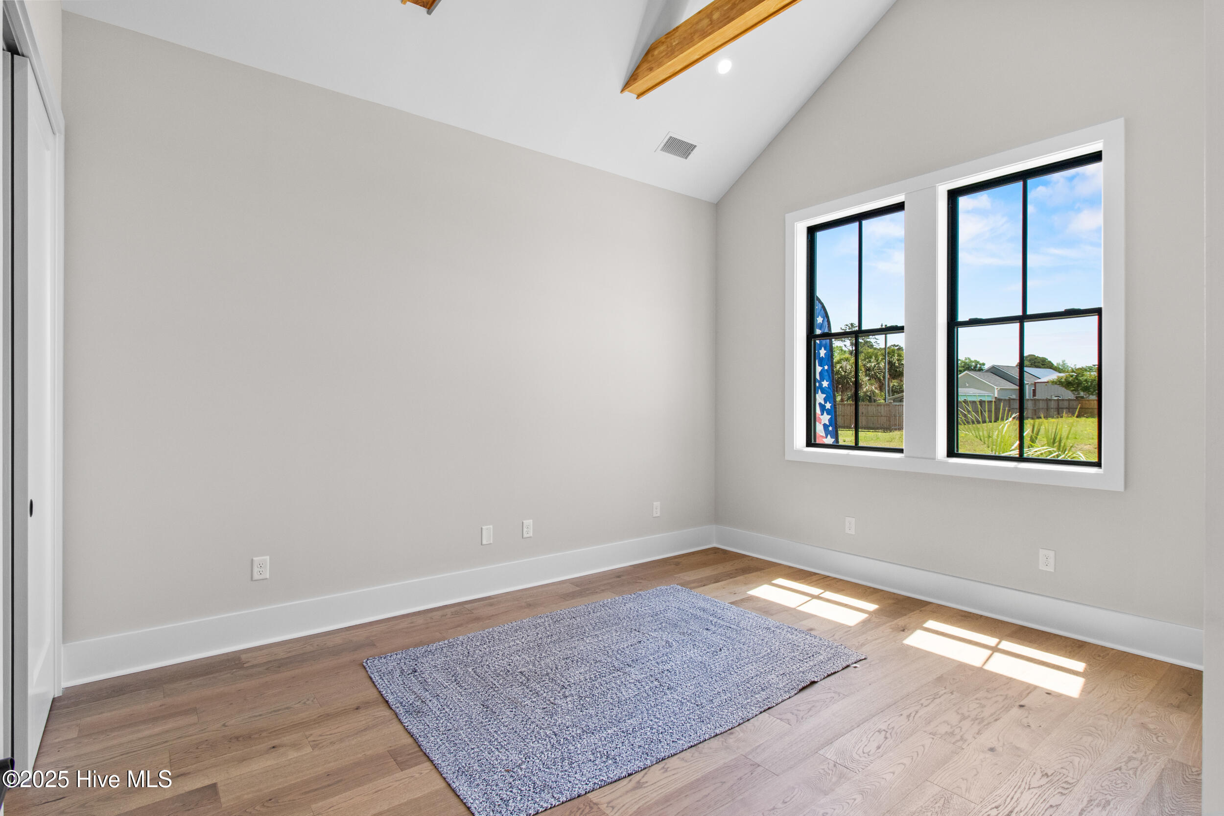Bedroom 3 downstairs with vaulted ceilings and beams, black windows!