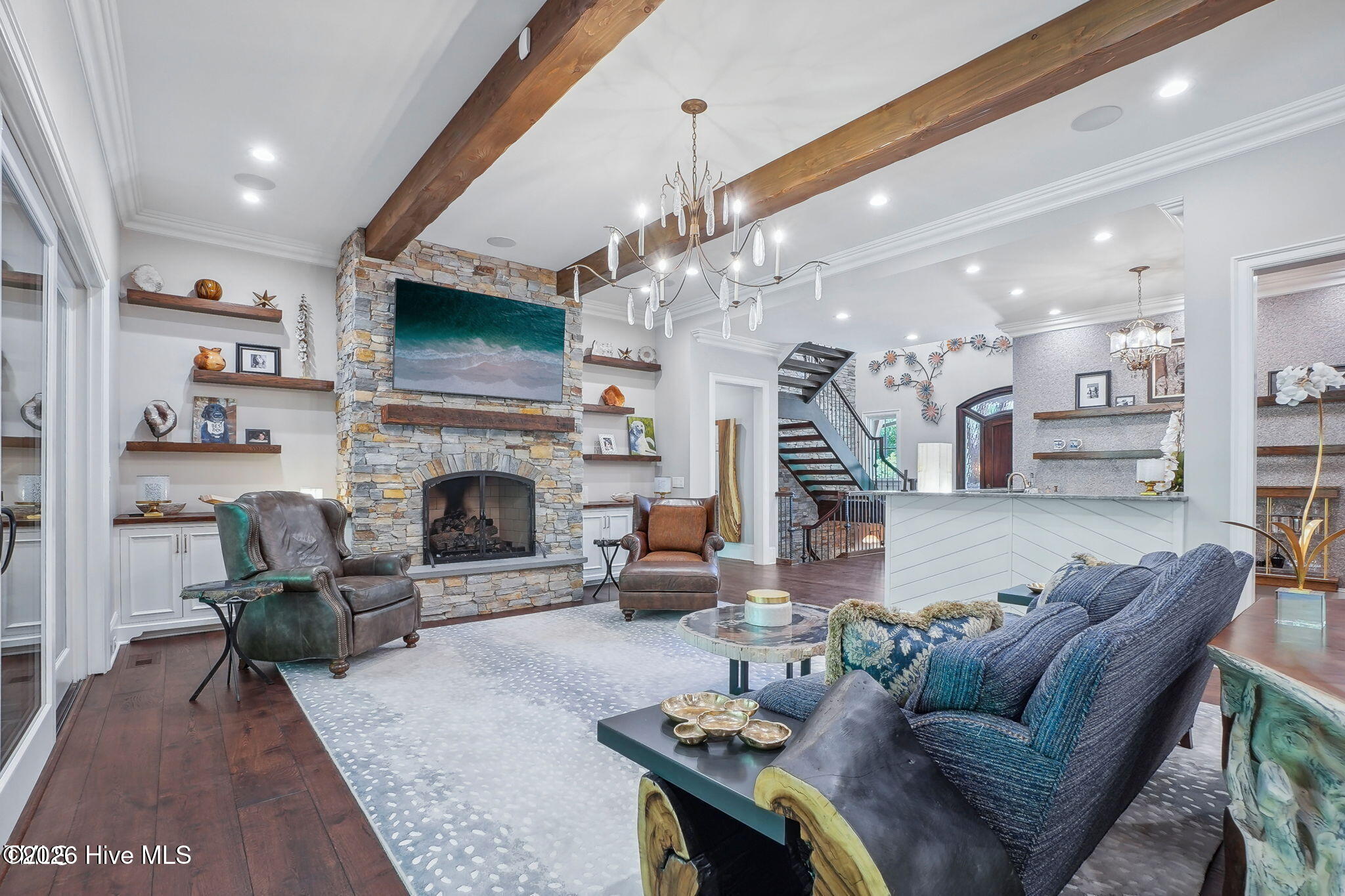 Great room has heavy wood beam accents with stone fireplace with gas logs