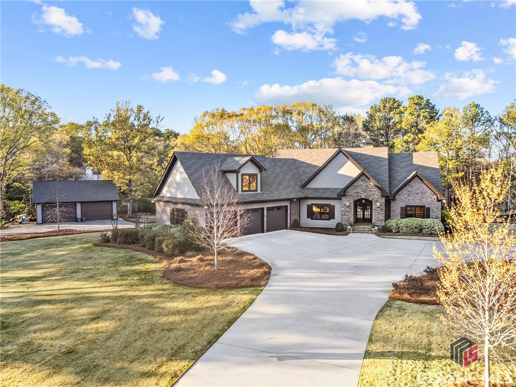 Gray stone-and-siding house with multiple gables, a curved driveway, and detached garage.