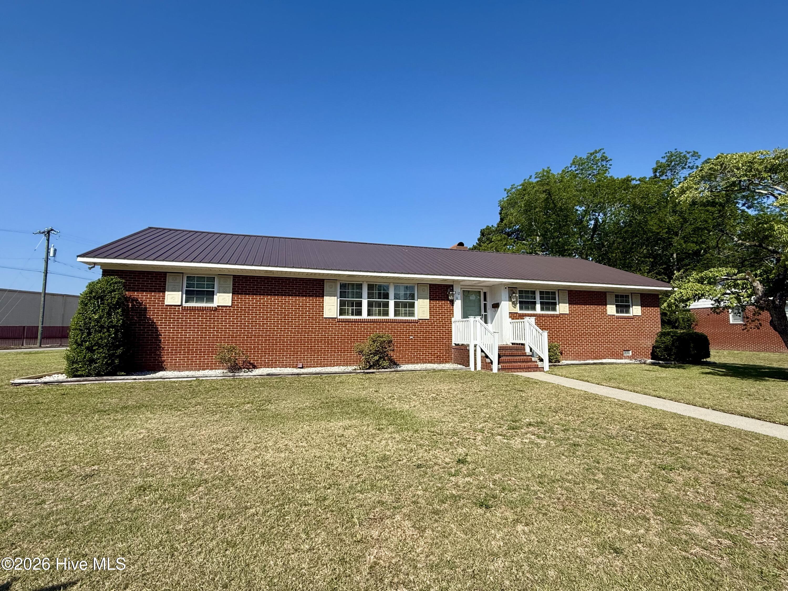 Welcome to the charming small town of Williamston, where this inviting 3-bedroom, 2-bathroom brick ranch sits proudly on a spacious corner lot, offering both comfort and opportunity. Step inside to discover beautiful hardwood floors flowing throughout the home, creating a warm and timeless feel. The open kitchen and dining area are designed for gathering and entertaining, highlighted by a cozy brick fireplace hearth. The kitchen is well-equipped with stainless steel appliances, blending modern convenience with everyday functionality.A bright sunroom provides the perfect place to unwind and leads seamlessly onto a large back deck, ideal for morning coffee, evening grilling, or hosting friends and family. The spacious primary suite offers plenty of closet space and a private en-suite bath featuring a luxurious jacuzzi garden tub, step-in shower, and direct access to a secluded screened-in porch -- your own peaceful retreat.Two additional guest bedrooms share a classic tiled hallway bathroom complete with a full tub/shower combination. The attached carport offers convenient covered parking for rainy days, and the home is truly move-in ready -- even including the washer and dryer.Outside, the detached garage expands the possibilities with two garage bays, a kitchenette area perfect for entertaining, and a dedicated workspace with a tool bench. Above the garage, you'll find a private living area featuring a living room, two bedrooms, and a full bathroom -- ideal for overnight guests, extended family, or flexible bonus space -- complete with its own central heating and air system powered by a separate heat pump for added comfort and independence.Enjoy a nicely fenced backyard, plus the convenience of city water and sewer. Don't miss your chance to own this versatile and welcoming property -- schedule your showing before it's gone!