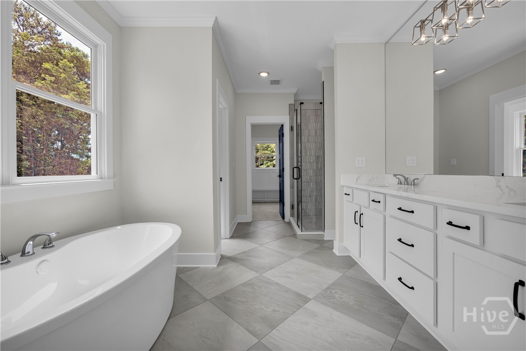 Light-filled bathroom featuring a freestanding soaking tub, dual vanity with white cabinetry, a glass-enclosed shower, and checkered tile flooring