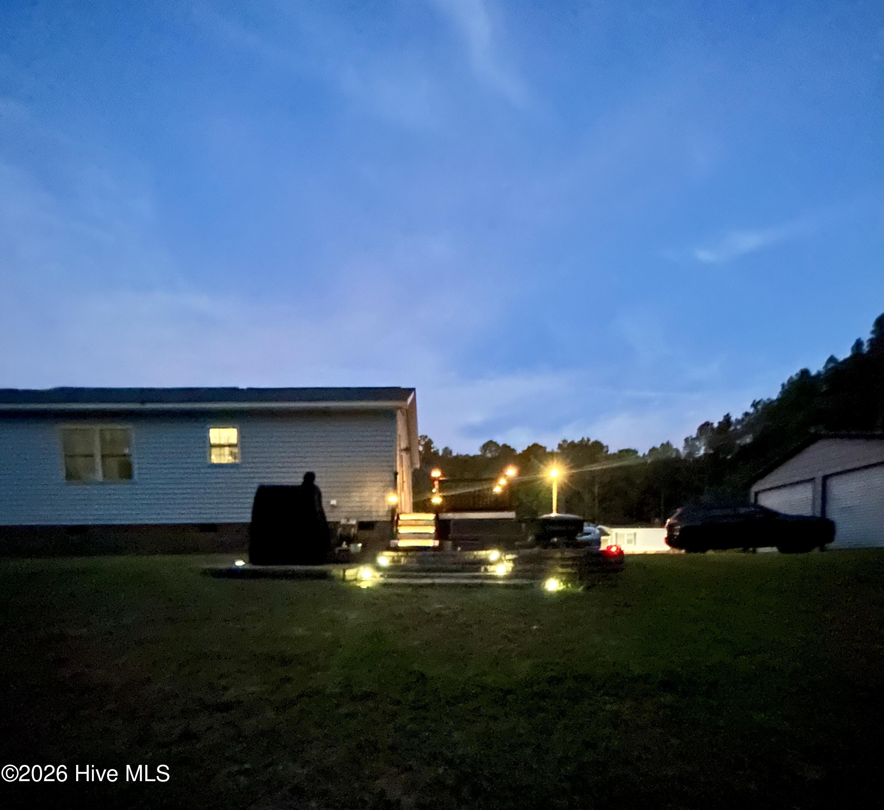 Full dusk view of patio lighting with grill and fire pit