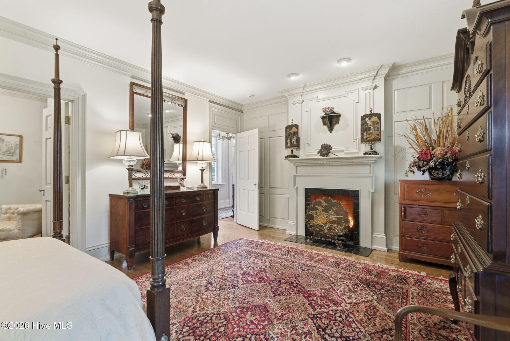 Primary Suite on the main level — celadon millwork, dentil cornice, a fireplace mantel built into the panels.