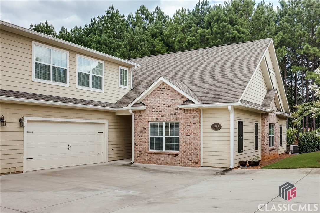 Enjoy life to the fullest and find a maintenance-free and serene lifestyle at the Cottages at Creekside.   This lovely home will capture your heart with its welcoming community, its comfortable, smart layout and its elegant features.  Built in 2016, this unit is perfectly clean and in immaculate, pristine condition.  The interior is flawlessly maintained, and the community association responsibly cares for the exterior, the grounds and the common areas.  This condo features one-level living with an open layout and spacious, handicap accessible rooms.  The living area is spacious and adjoins a dedicated dining space, a generously sized kitchen and a cozy breakfast nook or keeping room. You'll love the covered back patio, accessible through French doors from the great room with views of a beautiful grassy space and a natural wooded area behind the unit. The back patio offers a peaceful and private escape to sit and enjoy being outdoors. The kitchen is a dream with its long island with counter-height seating, gorgeous granite countertops, under-cabinet lighting and ample cabinets and storage.  The kitchen is complete with a large walk-in pantry, stainless appliances and a gas stove. A powder room and laundry room are located down a wide hallway that leads to the garage entry.  Just passed the door to access the two-car garage is a large storage room with tiled flooring - the perfect space to create a handy mudroom or drop space or to use as easily-accessed, temperature controlled storage.  Two bedrooms share a full hall bathroom, and the owner’s suite is tucked down a small hallway.  The owner’s suite offers a large bedroom with stylish tray ceilings and a luxurious bathroom that includes a spacious roll-in tiled shower, a double vanity, a soaking tub, a water closet, and a huge walk-in closet.  A wide carpeted staircase leads to a second floor - ready to be finished for an added bonus space or providing for additional storage as it is now. It's already framed and stubbed, so you could easily finish the space for a huge bonus room, another full bathroom, and two large walk-in closets —ideal for guest quarters or a fun hangout spot.  2688 Orchard Circle is a rare gem in a well-kept community. You'll have access to a clubhouse, two pools, tennis courts and a fitness center within an active community, and this home is located just minutes to destinations in Athens or Oconee County for shopping, restaurants and entertainment.