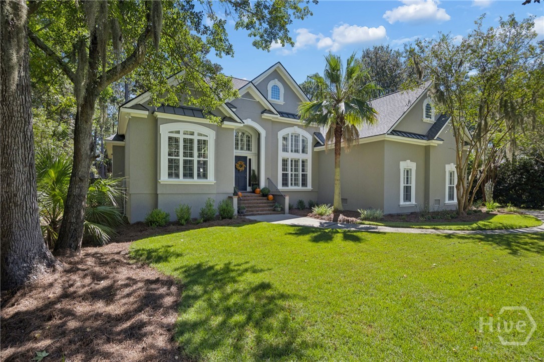 Gray house with white trim, arched windows, palm tree, and broad green lawn.