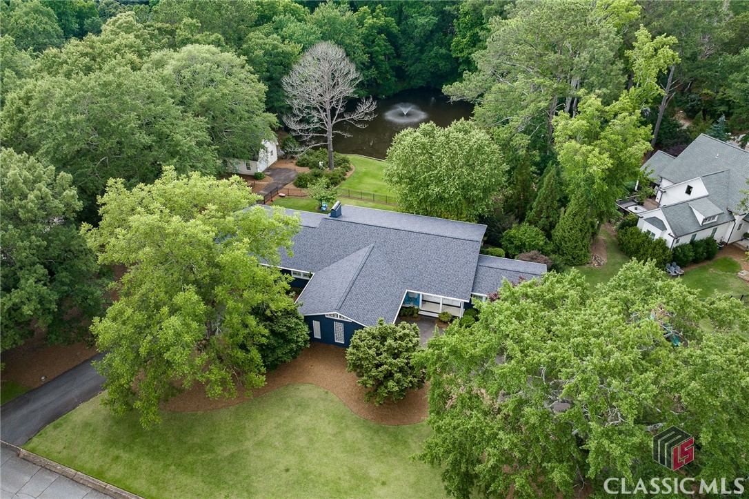 Welcome to 120 Witherspoon Rd, where mid-century charm meets modern living in one of Athens’ most beloved neighborhoods—Glenwood. This beautifully updated home sits on nearly an acre, offering breathtaking views of a serene pond right from your own backyard. Floor-to-ceiling windows line the back of the house, bringing in tons of natural light and making the most of those incredible views.Inside, the thoughtfully designed layout features 5 bedrooms and 3.5 baths. On the main level, you’ll find three bedrooms, including a spacious primary suite that feels like its own private retreat. Sliding doors open onto a balcony overlooking the pond, and with two walk-in closets and a spa-like ensuite (think marble floors, soaking tub, walk-in shower, and double vanities), it’s truly a dream. The other two bedrooms on this level share a stylish Jack and Jill bathroom, making the space both functional and inviting.Downstairs, the terrace level is made for relaxing and entertaining—with two additional bedrooms, a full bath, and a fantastic living area that includes a pool table, library, and built-in bar. French doors and a screened-in porch lead out to the fenced backyard, where you’ll find multiple brick patios perfect for hosting friends, sipping coffee, or soaking up the Georgia sunshine.At the heart of the home is the open-concept kitchen and living area, where vaulted ceilings with exposed beams and those incredible pond views steal the show. The kitchen is as beautiful as it is functional, with sleek white cabinetry, marble countertops, and high-end finishes that make cooking (or just hanging out) a joy. A formal living and dining room offer even more space to gather.And then there’s the charming one-bedroom, one-bathroom cottage—a standalone two-story space with 864 square feet that’s perfect for guests, in-laws, or even as a rental.This is truly a one-of-a-kind home in Athens, offering space, style, and a setting that’s hard to beat. Don’t miss your chance to see it in person—schedule a private showing today! xx