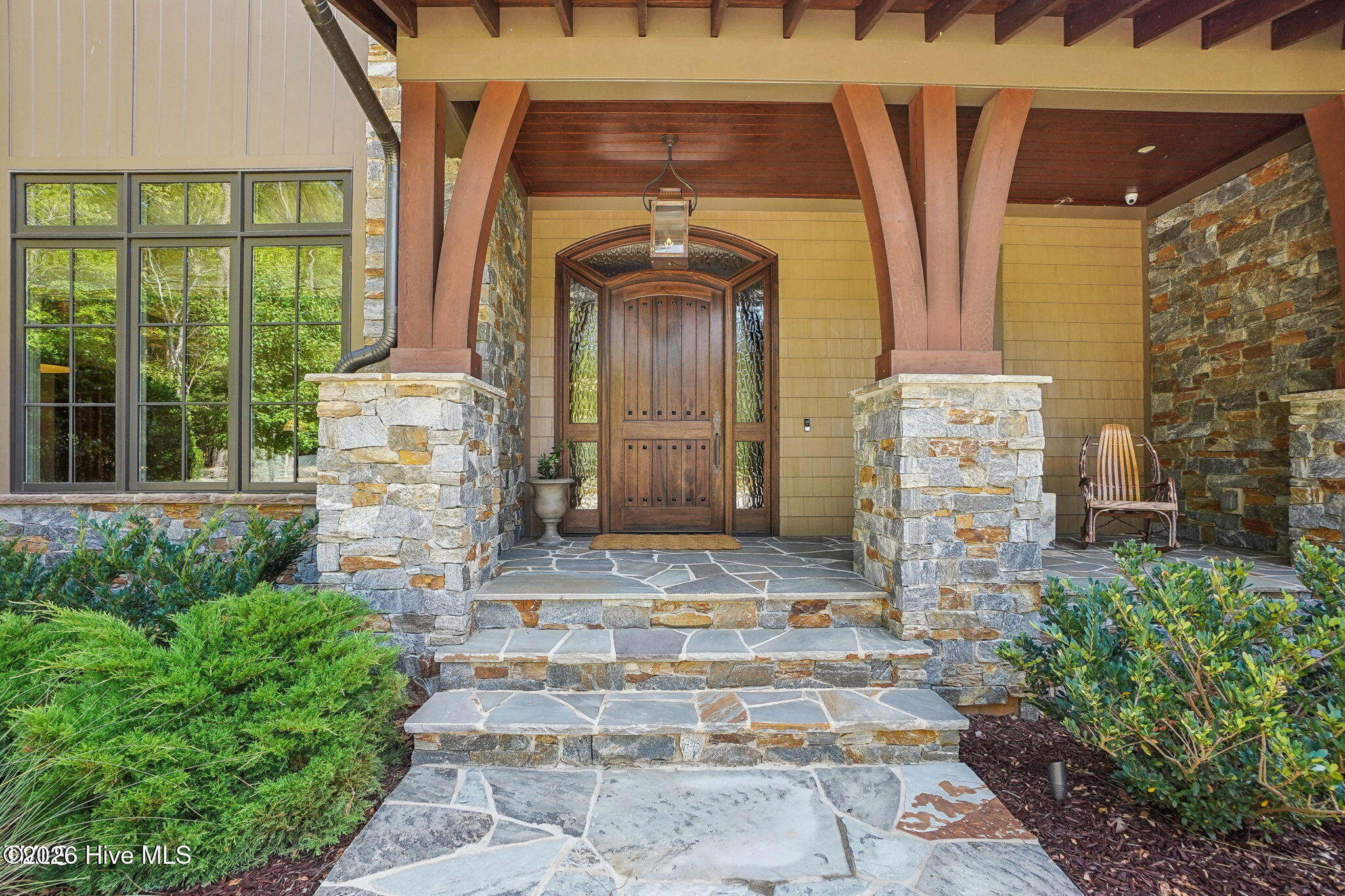 Stone and cement shake lodge style home with heavy timber accents. Oversized entry door with Rocky M