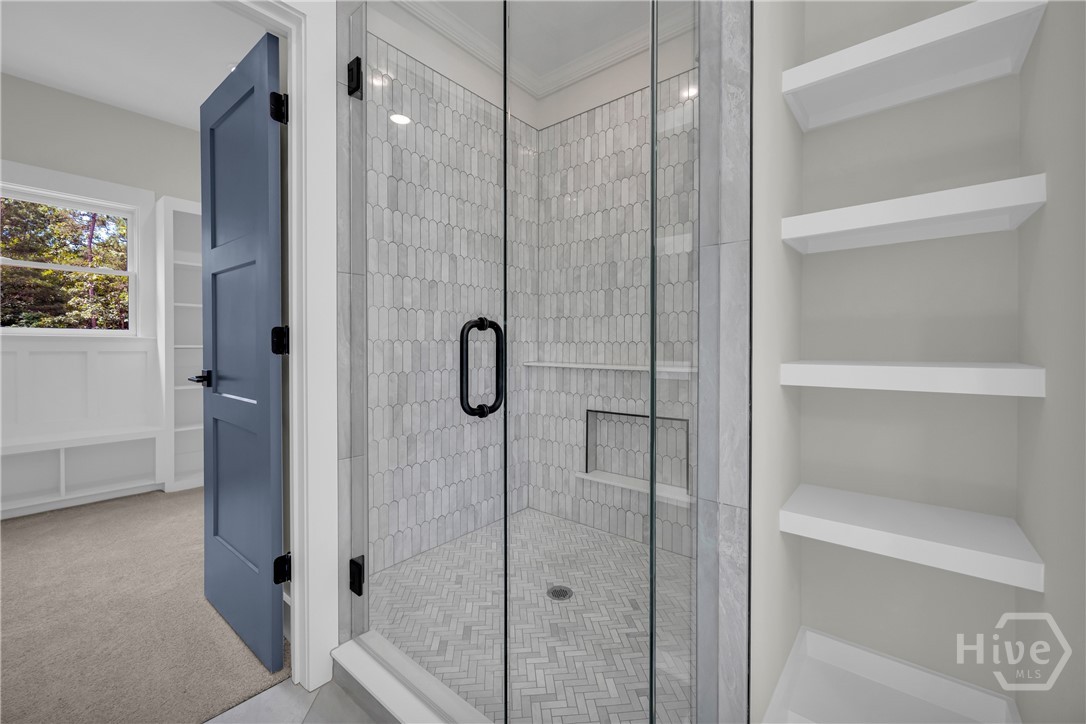 Glass-enclosed shower featuring picketed tile walls, a built-in shower niche, and matte black hardware