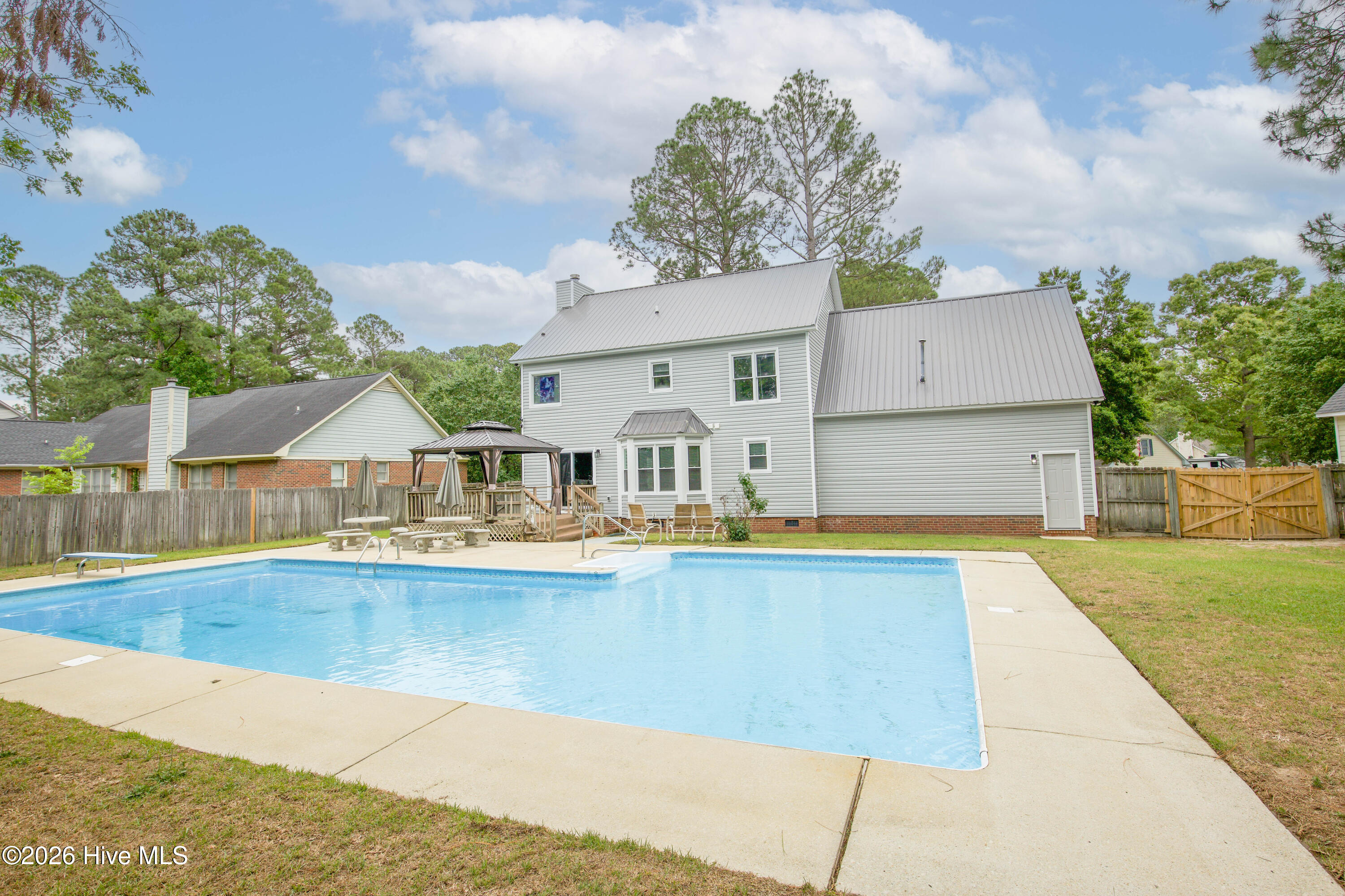 Wide backyard view showcasing the impressive in-ground pool, fenced yard, patio space, and rear exterior of the home. This property combines functional indoor living space with exceptional outdoor amenities designed for entertaining and enjoying the North Carolina climate year-round. Conveniently located near Fort Bragg, Raeford Road, shopping, dining, and the Fayetteville VA Health Care Center, this home offers the ideal blend of lifestyle, location, and flexibility for today’s buyers.