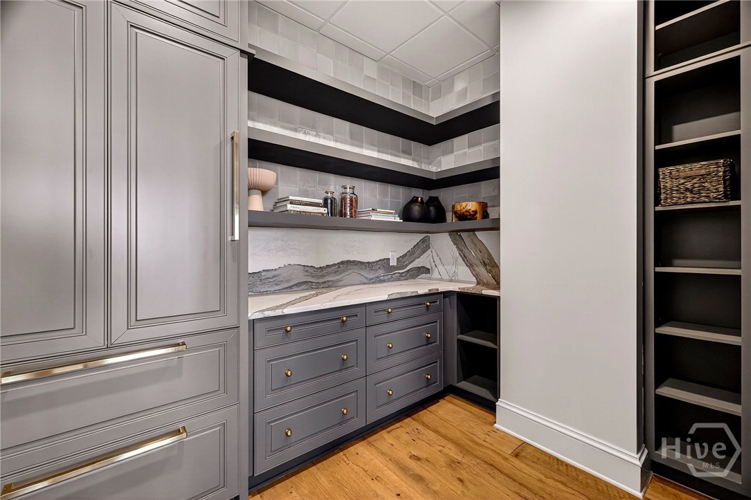 Pantry with open shelving and geometric tile. This thoughtfully designed pantry combines open shelving and concealed storage for optimal organization. Geometric tilework and layered cabinetry create visual interest, while the layout supports both display and utility. A stylish extension of the kitchen with elevated functionality.