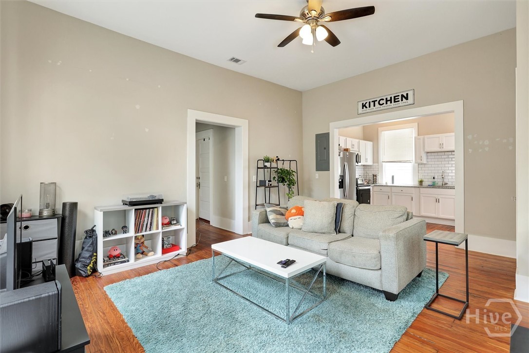 Bright living room with hardwood floors, high ceilings, and easy flow into the kitchen.
