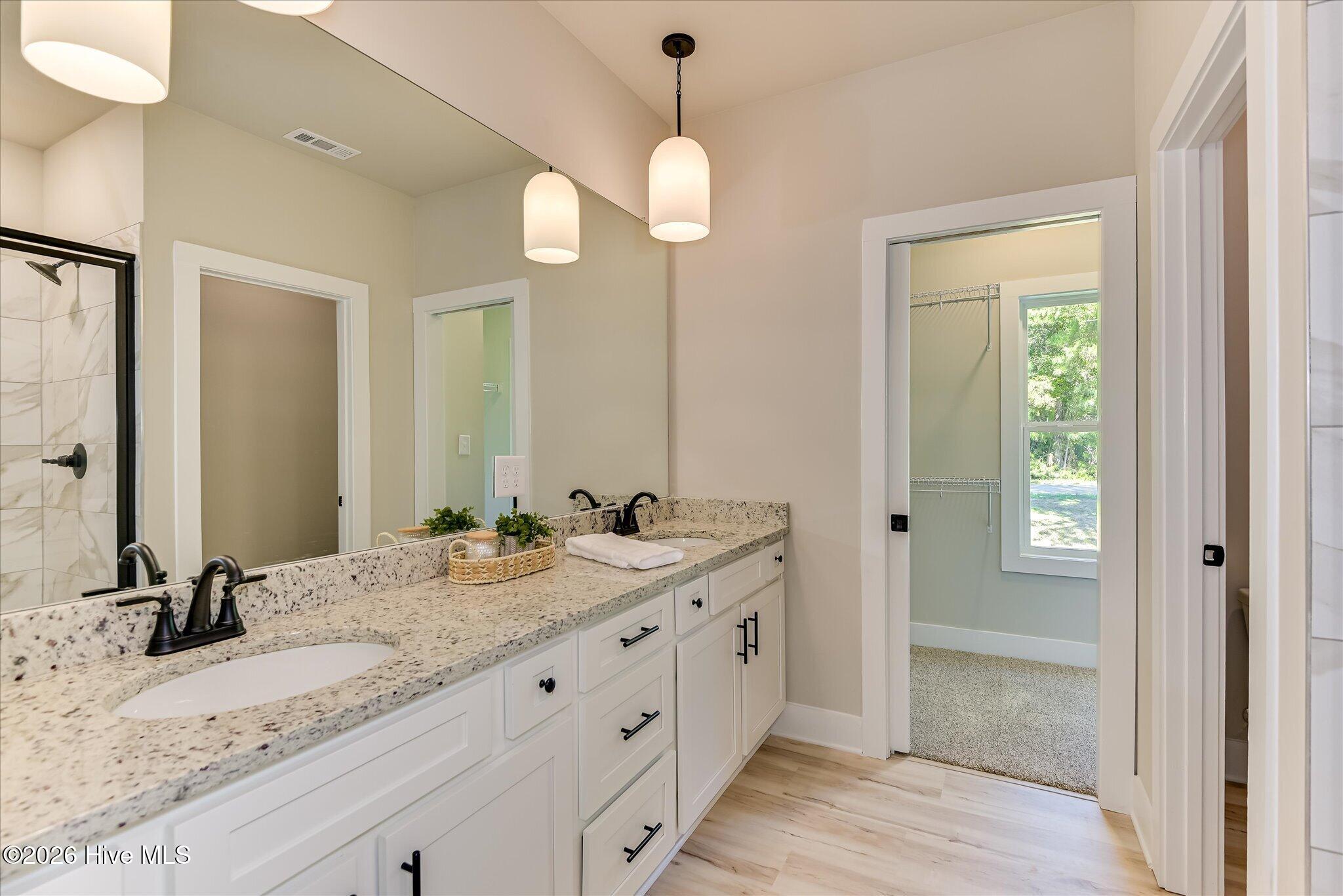 Primary Ensuite with double-sink vanity, tile shower, large walk-in closet