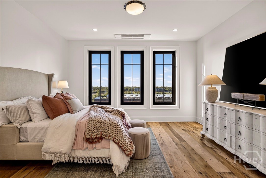 Bedroom 2 - This secondary suite is framed by tall black-trimmed windows that flood the space with natural light and offer serene landscape views. The layout includes a dedicated media wall and generous floor space, allowing for flexible furniture placement and restful ambiance. A bright, inviting haven with elevated architectural details.