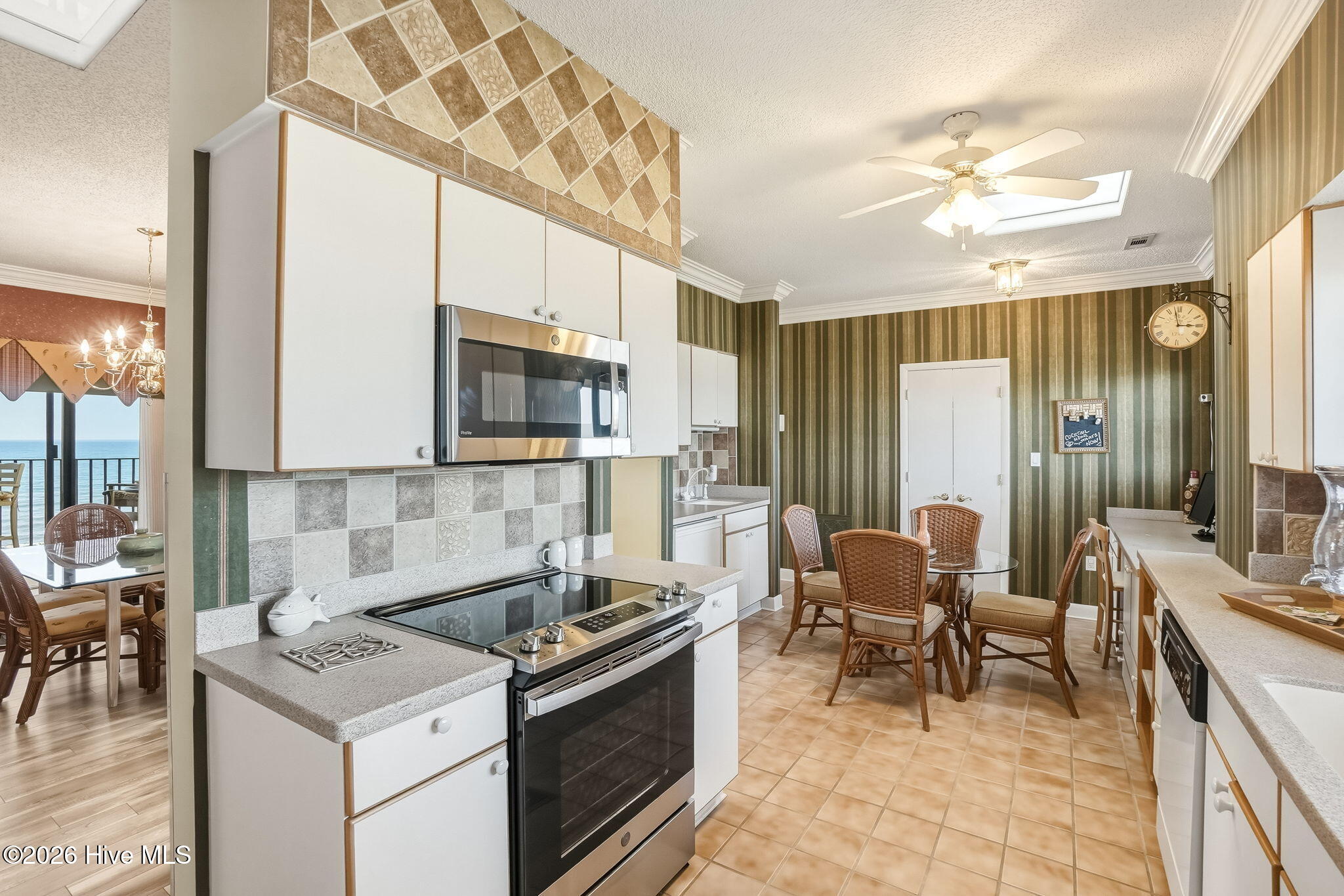Kitchen has a desk, stainless range, tile flooring and tons and tons of storage