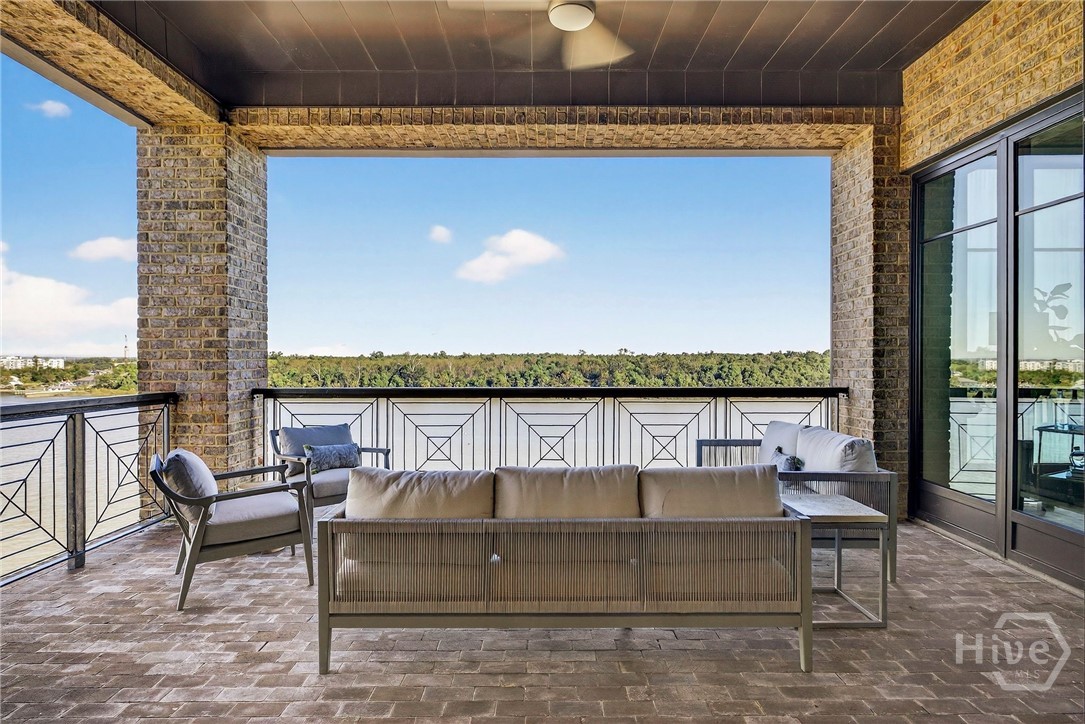 A tranquil outdoor retreat with lush views and direct access from the dining room area. The layout includes generous seating zones and a ceiling fan for comfort, while the geometric railing and brick flooring add architectural texture. Designed for peaceful mornings and sunset gatherings.