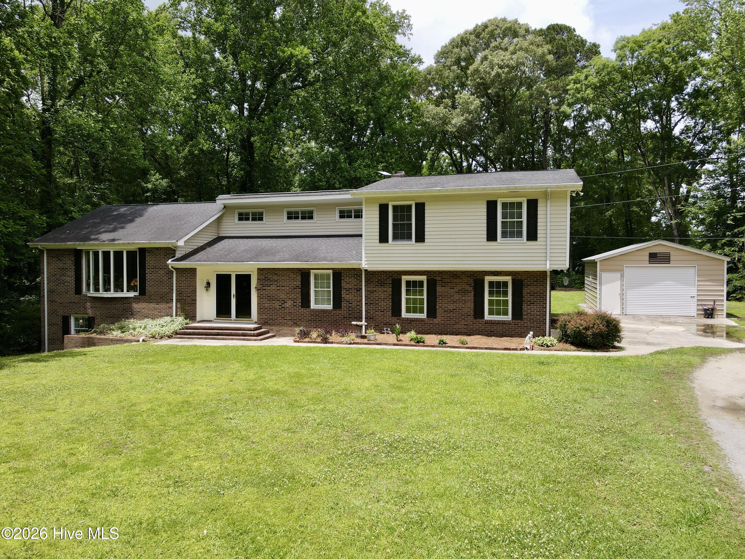 Welcome to peaceful Jamesville living, where this beautiful brick split-level ranch sits tucked among the trees on an open lot just off the Roanoke River. Surrounded by natural scenery, this property offers the perfect blend of privacy, comfort, and timeless charm.Step through the double entry doors into a grand foyer that sets the tone for the home's elegant and inviting design. Just beyond the foyer, the formal dining area is beautifully positioned in front of a large bay window, filling the space with natural light and offering serene views of the front yard and wooded surroundings.The updated kitchen is truly a chef's dream, featuring new granite countertops, updated cabinetry, new flooring, stainless steel appliances, two ovens, a propane gas range, dishwasher, built-in microwave, stainless refrigerator, and a spacious walk-in pantry. Designed for both everyday living and entertaining, the kitchen overlooks the warm and welcoming den/living area, complete with a brick wood-burning fireplace insert.The kitchen and living areas flow seamlessly to the back porch, where you can relax and enjoy views toward the Roanoke River. A covered back patio adds even more outdoor living space, making this home ideal for peaceful mornings, quiet evenings, or entertaining guests. This level also includes a private office and a full bathroom for added convenience.Downstairs, you will find an additional bedroom along with a large craft/hobby room that offers endless possibilities for storage, recreation, a workshop, studio, or flex space. Upstairs features two guest bedrooms that share a fully updated tile hallway bathroom. The spacious primary suite is also located upstairs and includes a large walk-in closet and a beautifully updated en-suite tile bathroom.The home also includes a two-car attached garage with new garage doors, offering convenient parking and additional storage. The laundry room is also located in the garage and includes laundry chutes from the upstairs bedrooms along with a large garden sink, making everyday chores a little easier.Outside, the property continues to impress with beautiful flower beds, peaceful natural surroundings, and a detached metal garage building that provides even more space for storage, hobbies, equipment, or workshop needs.With its scenic setting, spacious layout, updated finishes, attached and detached garage space, and peaceful location near the Roanoke River, this Jamesville home is a rare opportunity to enjoy comfort, privacy, and nature all in one place. Come see all of what this home can offer you and your family, and schedule your private tour today!